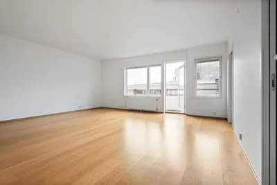 An empty room with hardwood floors, white walls, and no furniture yet