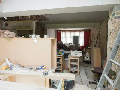 A room mid-renovation with a ladder, exposed wood framing, and construction materials