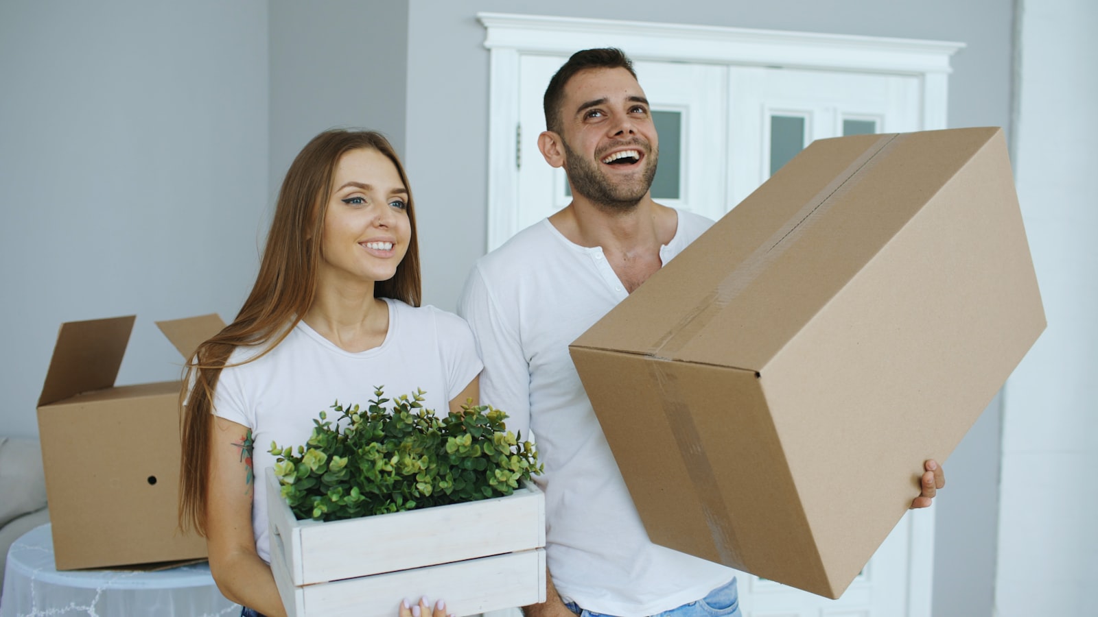 A couple holding moving boxes in their new home